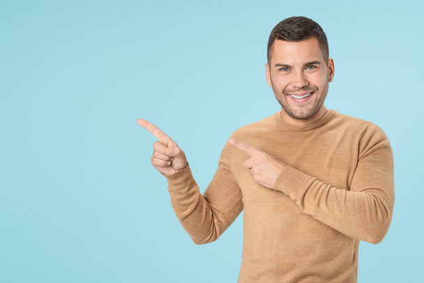 Young adult man pointing with fingers and looking at camera isolated on blue background - Foto, afbeelding