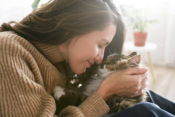 Charismatic young woman playing with her adorable cat. - Photo, Image