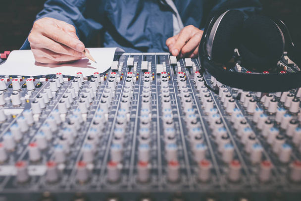 男性プロのソングライタープロデューサーが録音スタジオでオーディオミキシングコンソールに曲を書き - 写真・画像