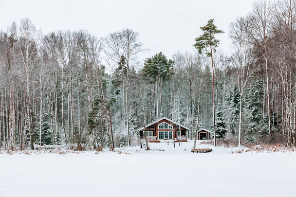 Wooden cottage in snow covered forest in Finland. - Fotografie, Obrázek