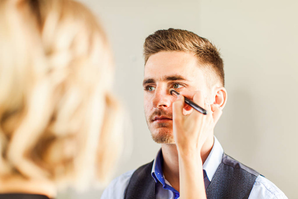 Handsome man doing makeup for fashion photography studio. - Foto, afbeelding