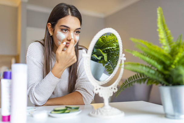 Photo of brunette girl touching hands her face. Skin care concept. Beautiful young woman with facial mask, beauty treatment. An attractive young woman with a face mask. - Φωτογραφία, εικόνα