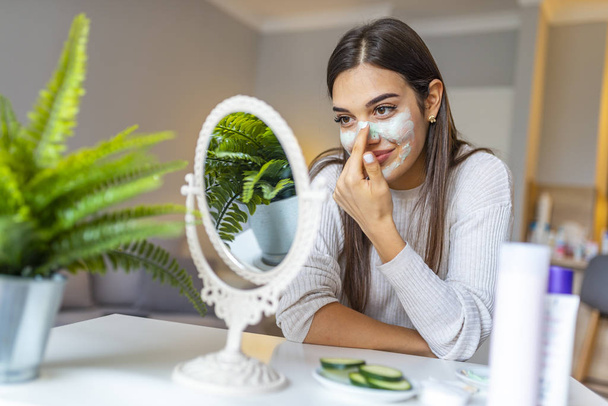 Great skin that makes you smile. Woman with a mask on her face. Spa Woman applying Facial clay Mask. Beauty Treatments. Close-up portrait of beautiful girl with applying facial mask - 写真・画像