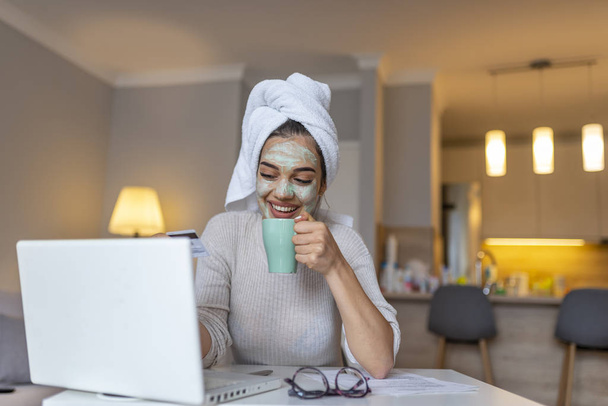 Business female freelancer at home.Casual dressed woman take care of her face and hair while work on laptop. Woman using laptop in livingroom. Woman wearing facial mask enjoying at home and using her laptop - Foto, Imagem