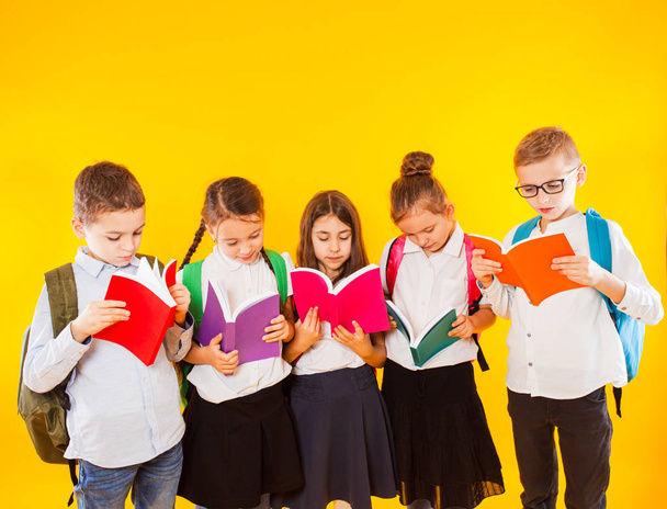 Group of classmates reading book over yellow background. - Φωτογραφία, εικόνα