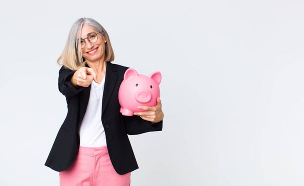 middle age woman with a piggy bank. savings concept - Фото, изображение