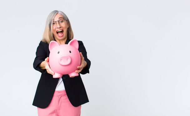 middle age woman with a piggy bank. savings concept - Фото, изображение