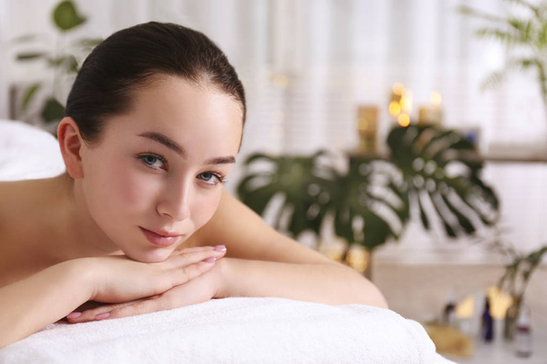 Brunette female with relaxed facial expression lying on a massage table. - Fotoğraf, Görsel