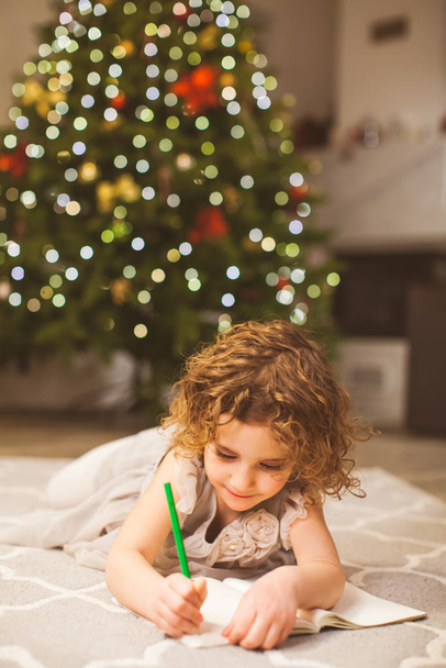 Christmas holidays and childhood concept with girl, writing on a floor - Photo, image