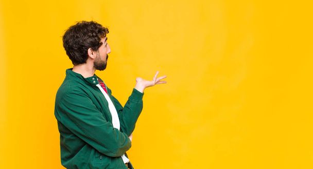 young crazy bearded man against orange wall copy space. - Photo, Image