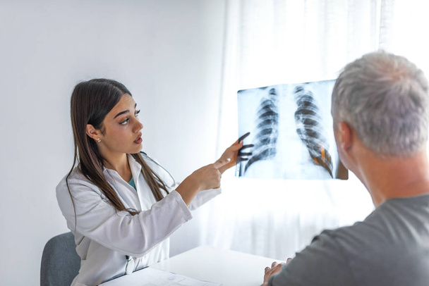 Female doctor explaining checkup result to her patient using x-ray image. Medicine professional showing diagnosis of x-ray image to patient sitting at clinic. - Foto, immagini
