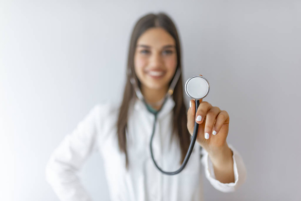 Portrait of happy successful female doctor. Medical concept of young beautiful female doctor in white coat, waist up. Woman hospital worker looking at camera and smiling, studio, grey background - Photo, image