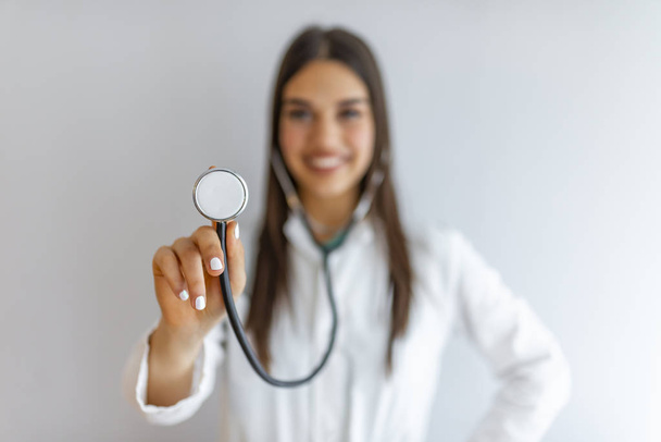 A female doctor holds her stethoscope to insinuate that it's time for a check up in clinic banner panoramic crop for copy space. Smiling medical woman doctor. Isolated over grey background - Fotografie, Obrázek