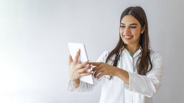 Healthcare, technology and medicine concept - smiling female doctor with stethoscope and tablet pc computer. Young happy medical worker using tablet computer. - Фото, зображення