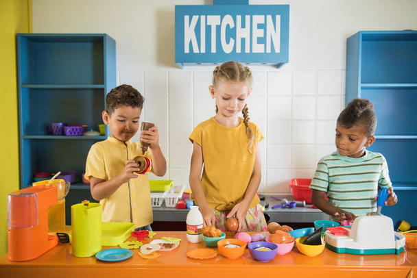 Παιδιά που παίζουν με πλαστικό φαγητό στον παιδικό σταθμό. - Φωτογραφία, εικόνα
