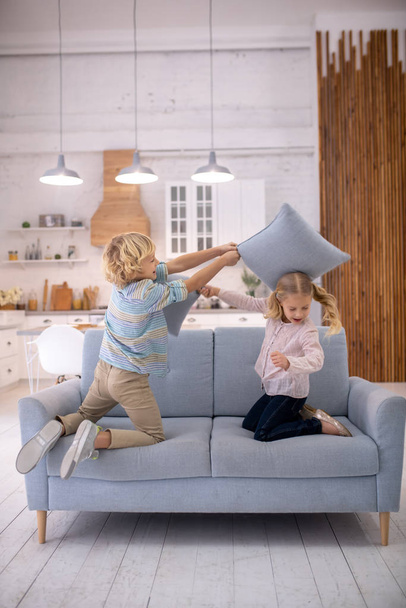 Blond cute boy putting a pillow on his sisters head - Photo, Image