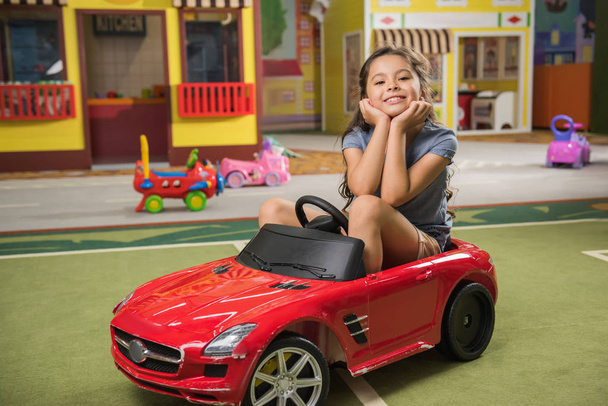 Schattig kind in speelgoed auto glimlachen op de camera in het speelcentrum. - Foto, afbeelding