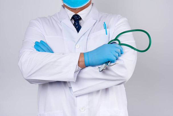 médico varón adulto con un abrigo médico blanco se para y sostiene un género
 - Foto, imagen