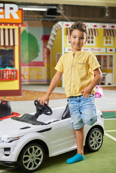 Kleiner Junge mit einem großen Spielzeugauto schaut in die Kamera. - Foto, Bild