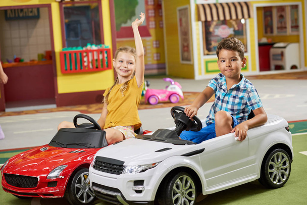 Діти грають разом сидячи в іграшкових автомобілях
. - Фото, зображення