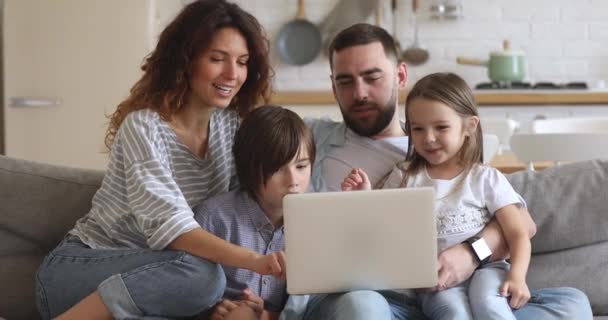 Smiling family of four using laptop, shopping at home. - Video, Çekim