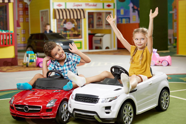 Kids playing together sitting in toy cars. - Foto, imagen