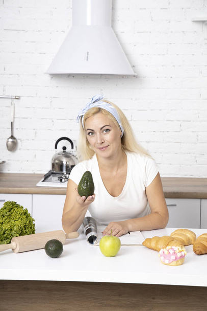 The girl is holding an avocado. Woman cutting fresh avocado at t - Photo, Image