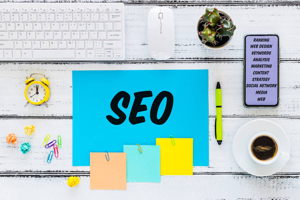 SEO inscription on a sheet lying on the desk.  Search Engine Optimization.  Creating more traffic on websites.  Market analysis, Top view.  telephone with goals, watch, keyboard, office accessories - Fotó, kép