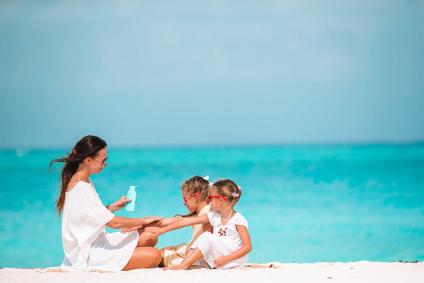 Jeune mère appliquant de la crème solaire sur le nez de sa fille sur la plage. Protection solaire - Photo, image