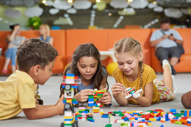 Meninos e meninas brincando com brinquedos de bloco na sala de jogos
. - Foto, Imagem