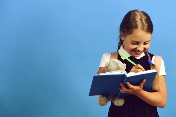 Pupil in school uniform with braids and book - Foto, afbeelding
