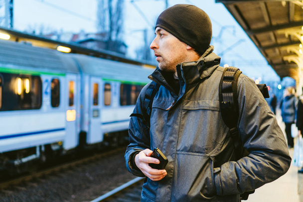Estação Ferroviária em Sopot, Polônia, Europa. Um homem atraente à espera na estação de comboios. Pensando em viagem, com mochila. Fotografia de viagem. turista com mochila stand na plataforma da estação ferroviária
 - Foto, Imagem