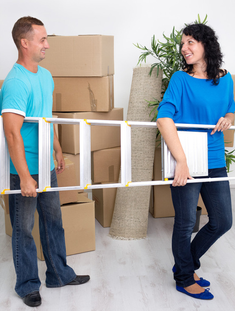 jonge gelukkige paar met een ladder in zijn handen in nieuwe huis - Foto, afbeelding