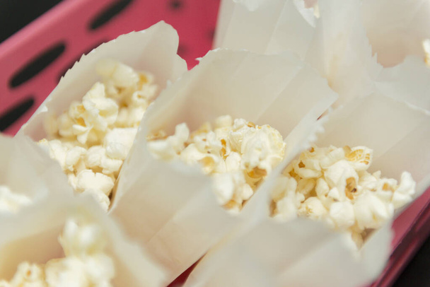 Ansicht von Popcorn hausgemacht in weißer Tüte auf schwarzem Tischhintergrund. - Foto, Bild