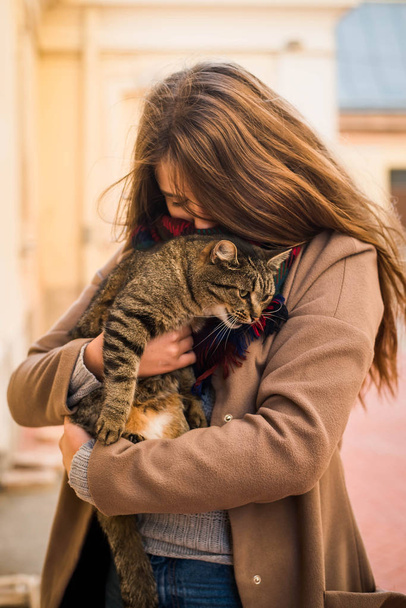 молодая привлекательная девушка обнимает кошку на фоне города
 - Фото, изображение