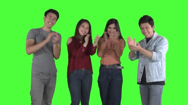 Grupa młodych ludzi uśmiechających się i bijących brawo przed kamerą w studio. Strzał w rozdzielczości 4k z zielonym tle ekranu - Materiał filmowy, wideo