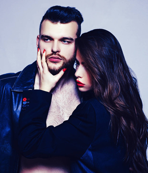 She adores male brutal beard. Passionate hug. Couple passionate people in love. Man brutal well groomed macho and attractive girl cuddling. Girlfriend passionate red lips and man leather jacket - Fotografie, Obrázek