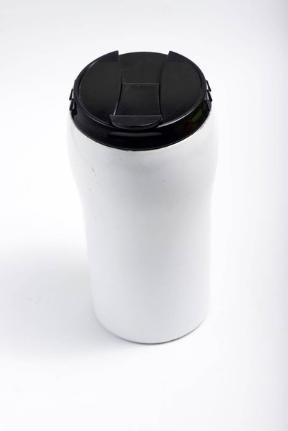 Valkoinen ruostumattomasta teräksestä valmistettu tumbler, jossa musta kansi
 - Valokuva, kuva