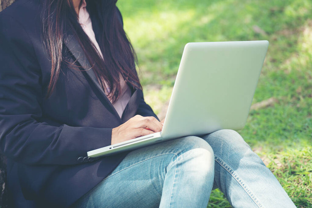 Smart woman working outdoor. Freelance Using laptop smart tablet and smart phone lay down on green grass field reading spreadsheet. work from home business concept. - Photo, Image