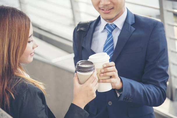 Młodzi azjatyccy biznesmeni uśmiechnięci i zrelaksowani trzymający filiżankę kawy przed pójściem do pracy. Koncepcja stylu życia biznesu - Zdjęcie, obraz