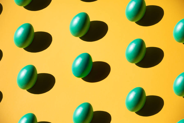 Цветные пасхальные яйца на желтом фоне с резкими тенями
 - Фото, изображение
