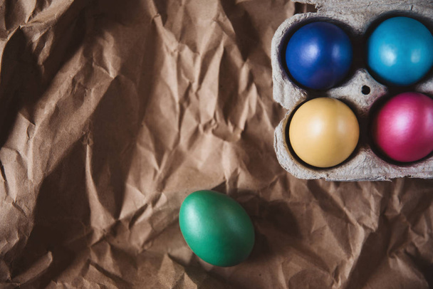 Цветные пасхальные яйца на коричневой морщинистой бумаге
 - Фото, изображение