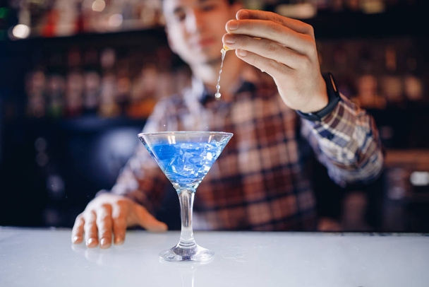 Large cocktail in martini glass with droplets of spray is prepared by barman - 写真・画像