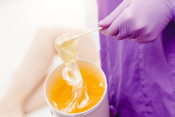 Women beautician holds jar wax of paste for sugar depilation shugaring, white background - Foto, Imagem