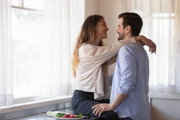 Happy young couple hug cooking breakfast in kitchen - Photo, image