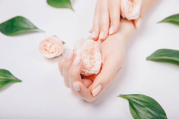 Concept beauty. Beautiful stylish trendy female pink manicure with flower on background, top view - Foto, immagini