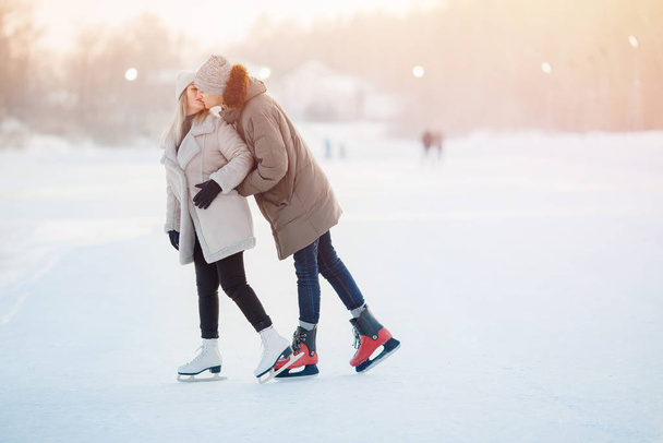 Χειμωνιάτικα πατίνια, ερωτευμένο ζευγάρι να κρατιέται χέρι-χέρι και να κυλάει. Εκπαίδευση έννοιας - Φωτογραφία, εικόνα