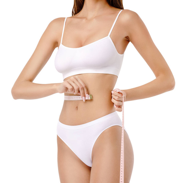 Slim tanned womans body over gray background - waist measurement - Foto, imagen