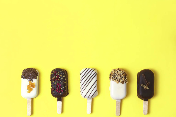 Chocolate popsicle. ice cream stick on yellow, lemon background, pastel color. Place for text, copy space. - Photo, Image