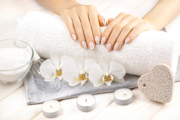 mooie franse manicure met orchidee, kaars en handdoek op de witte houten tafel. - Foto, afbeelding